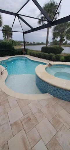 A pool and attached spa on a travertine deck in Lee County